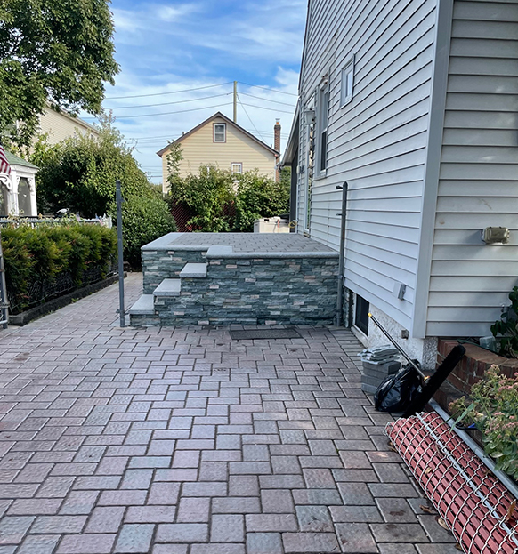 backyard of a house with stairs and brick floor in gray tones